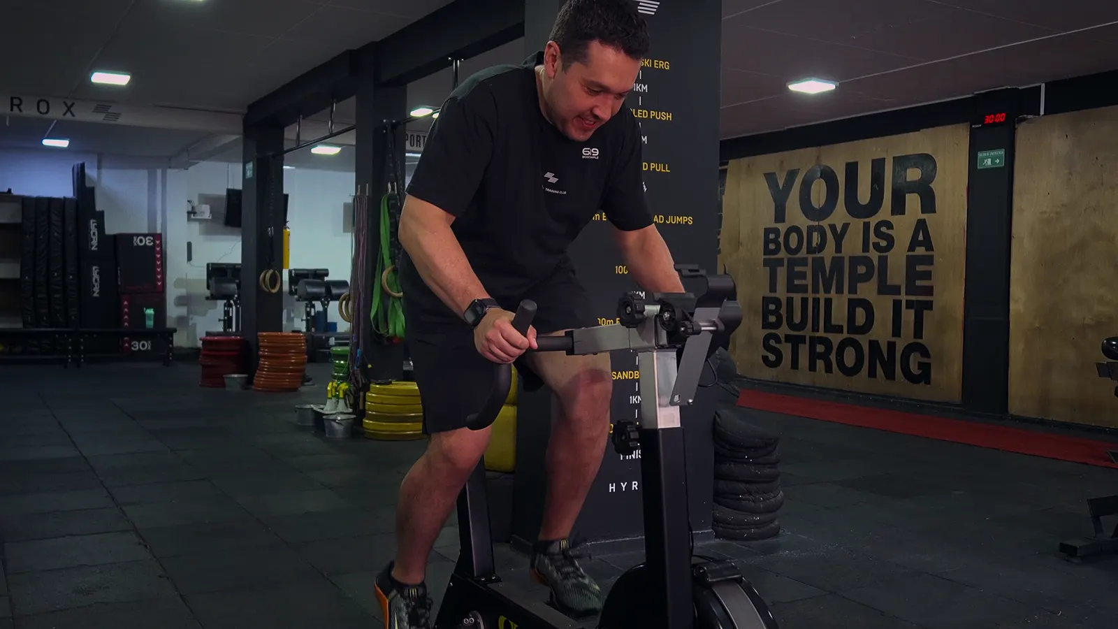 Atleta en la bici frente al mural «Your body is a temple, build it strong»
