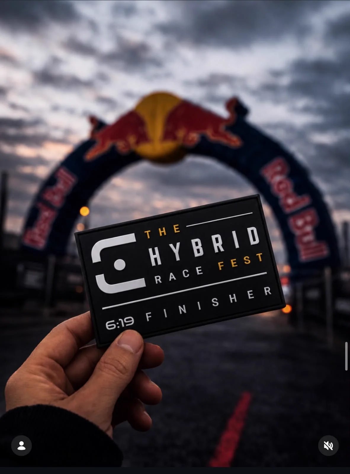Parche de finisher de The Hybrid Race Fest sostenido frente al arco de meta