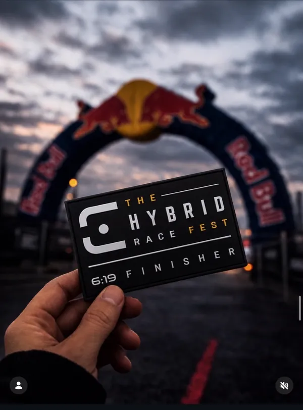 Parche de finisher de The Hybrid Race Fest frente al arco de meta